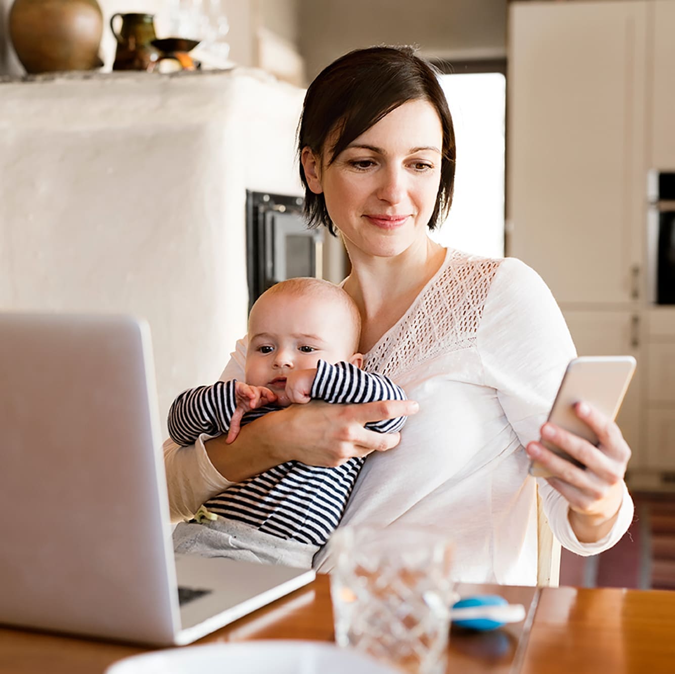 Mortgage Advice on your Doorstep | Mum with a baby sitting at a kitchen table with her phone and a laptop