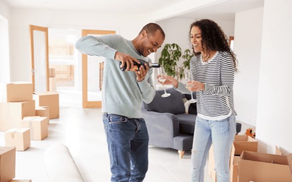 Happy couple celebrating in their new home with bubbles