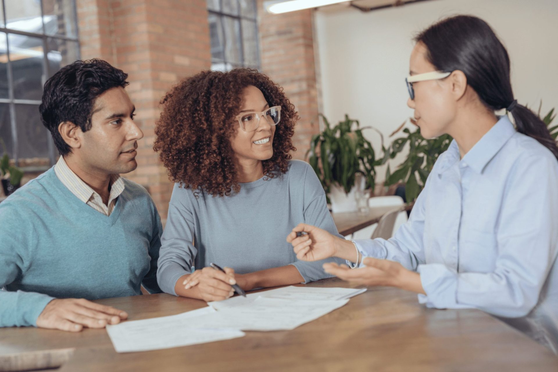 Secured loans | A couple signing a contract sat at a table with a sales woman