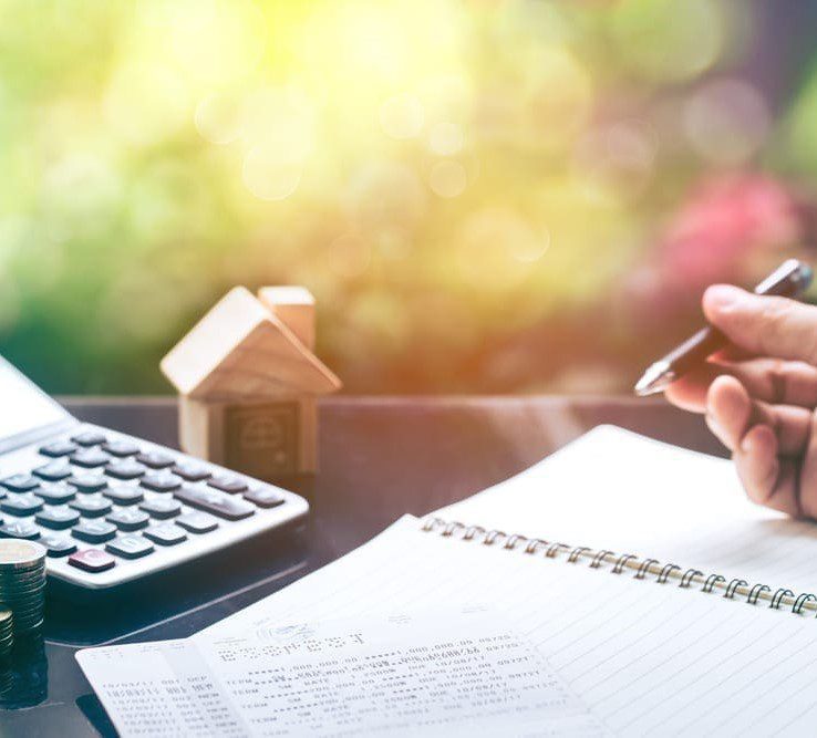 What to do if you can't afford a mortgage | Image of a calculator with stacked coins and person using a notepad and pen