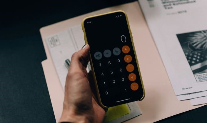 Widget Self-Employed | Person using a mobile phone calculator with paperwork