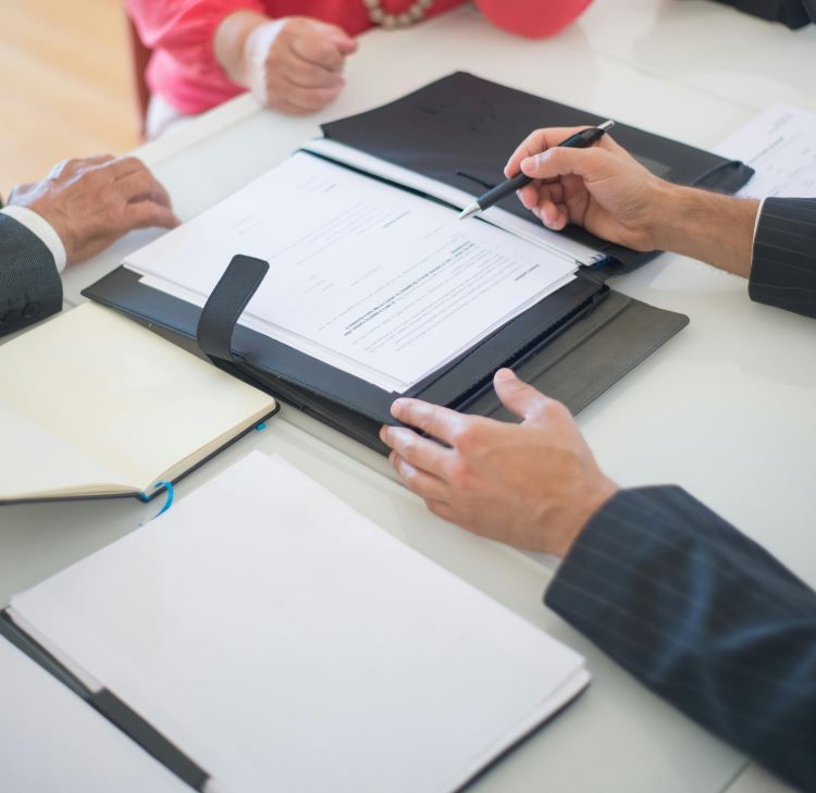 People in suits signing a document over a table